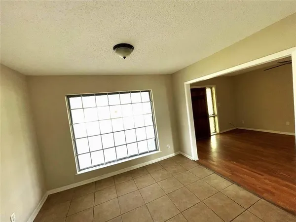 an empty room with wooden floor and windows with curtains