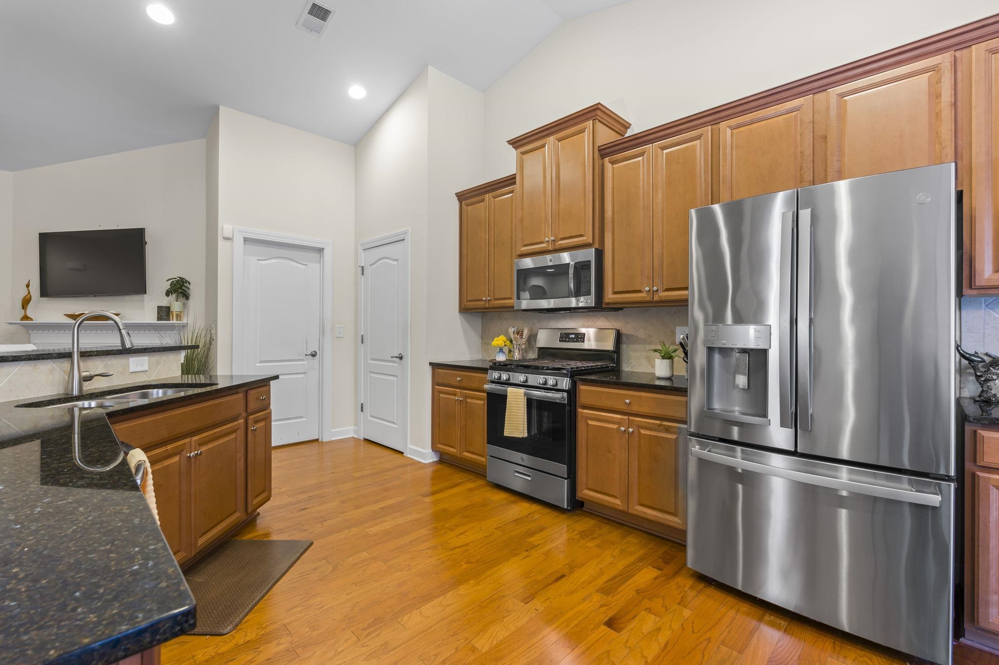 2015 Oxford Street Myrtle Beach, SC 29577 - Photo 10 of 40 Kitchen with appliances with stainless steel finishes, dark stone countertops, brown cabinets, light wood-style floors, and high vaulted ceiling