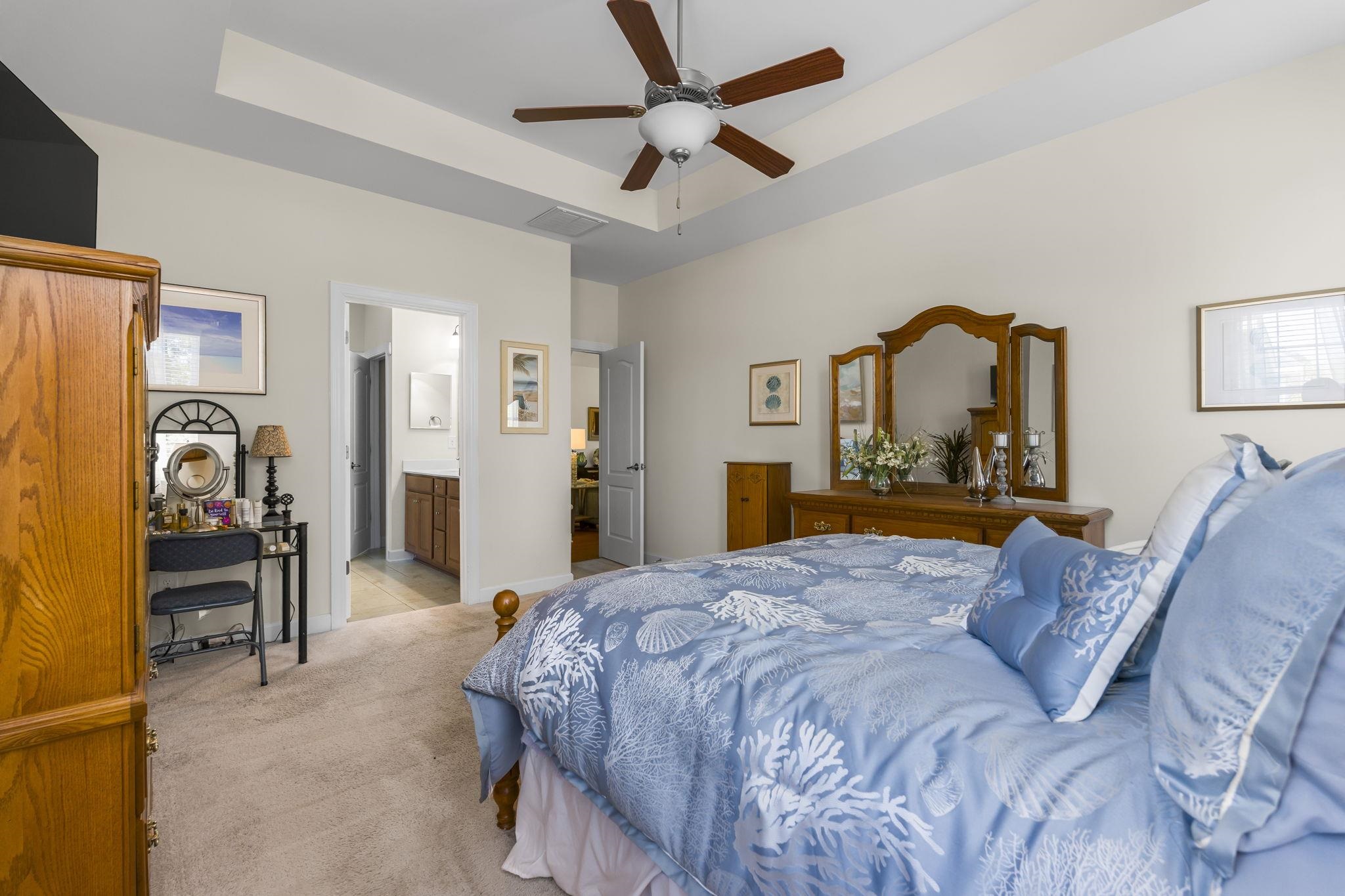 2015 Oxford Street Myrtle Beach, SC 29577 - Photo 18 of 40 Bedroom featuring a raised ceiling, a ceiling fan, light colored carpet, and ensuite bath