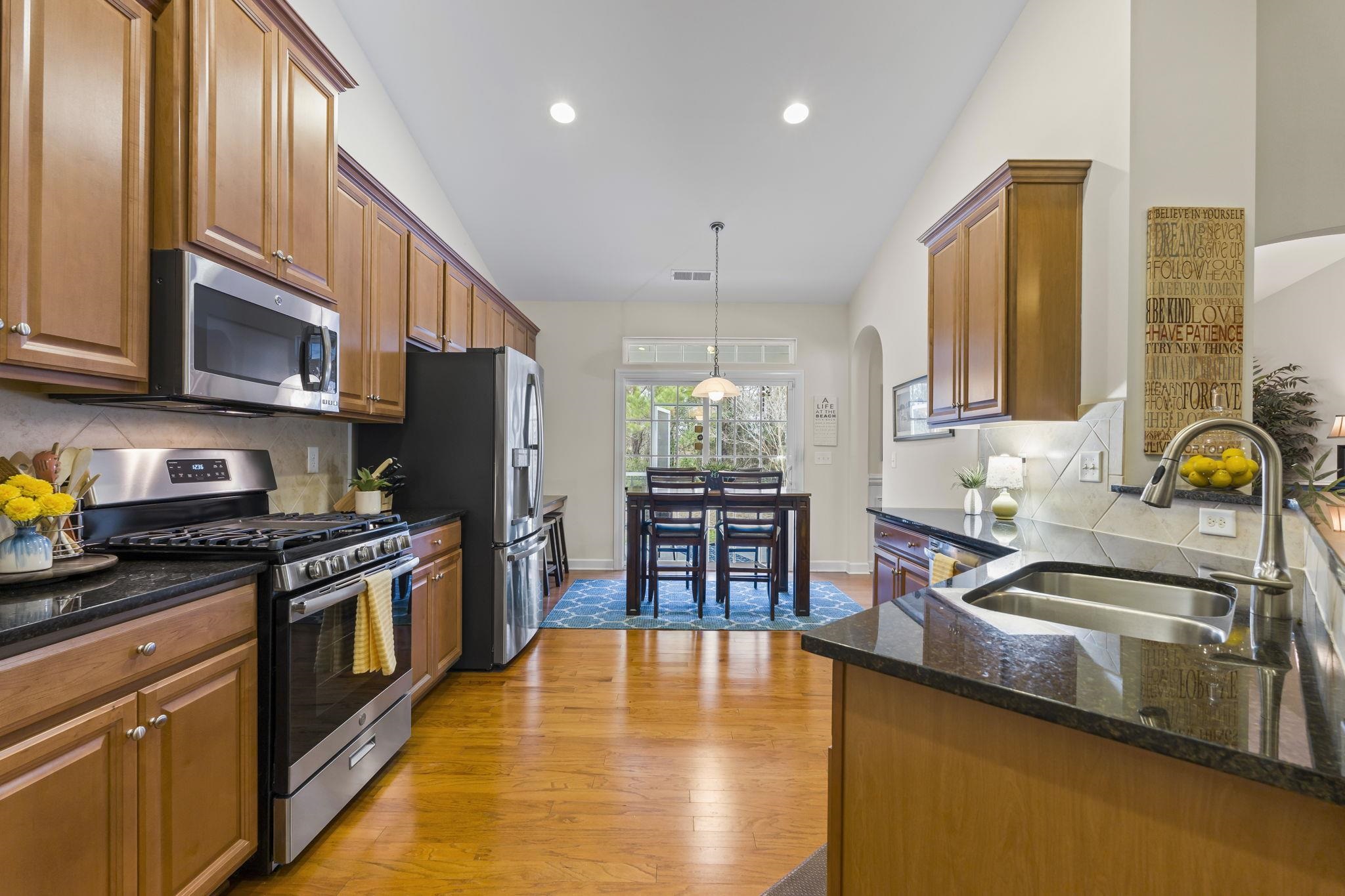 2015 Oxford Street Myrtle Beach, SC 29577 - Photo 9 of 40 Kitchen with backsplash, appliances with stainless steel finishes, dark stone countertops, brown cabinetry, and lofted ceiling