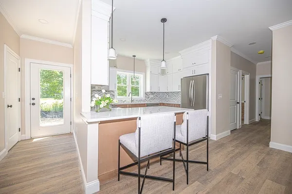 a kitchen with stainless steel appliances a dining table chairs a sink and dishwasher a refrigerator with wooden floor