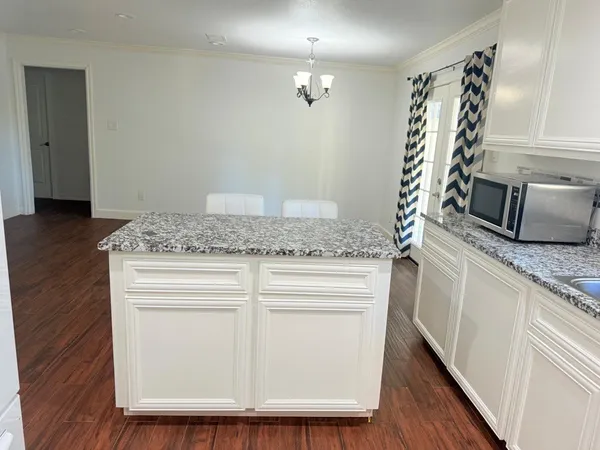 a kitchen with a granite countertop white cabinets and a wooden floor