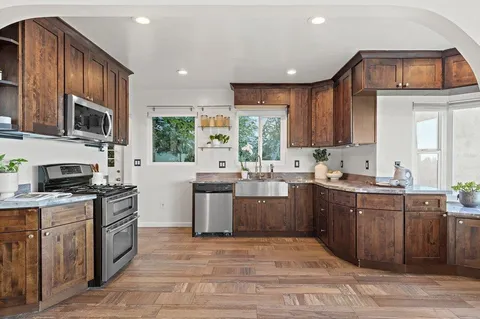 a kitchen with kitchen island granite countertop a sink cabinets and stainless steel appliances