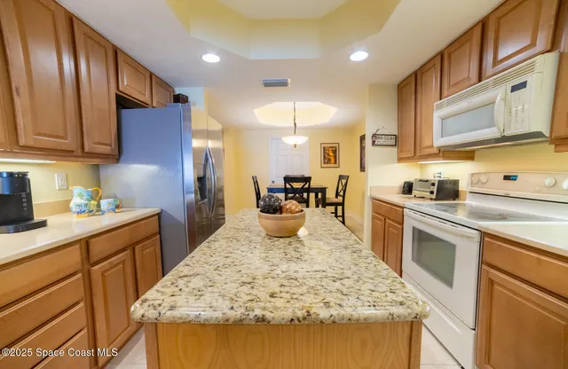 a kitchen with kitchen island granite countertop wooden cabinets a sink and dishwasher
