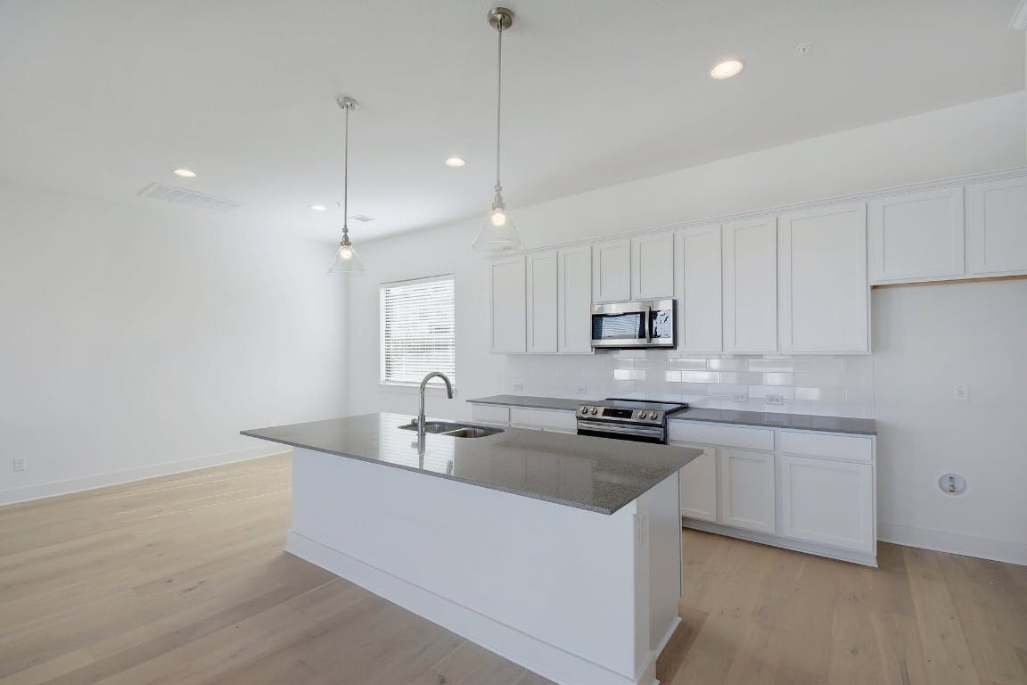2050 Lohmans Spur Road, Unit 402 Austin, TX 78734 - Photo 1 of 39 a kitchen with kitchen island a sink a stove and cabinets