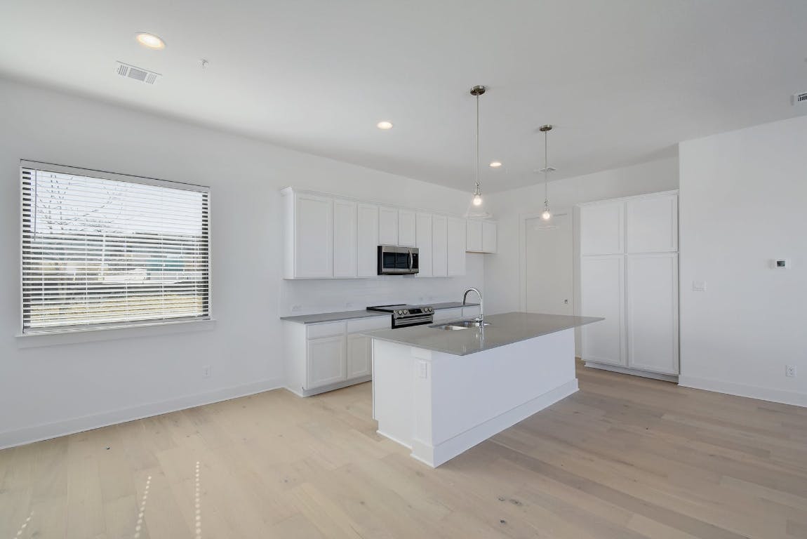 2050 Lohmans Spur Road, Unit 402 Austin, TX 78734 - Photo 14 of 39 a large white kitchen with a large window a sink and a stove top oven