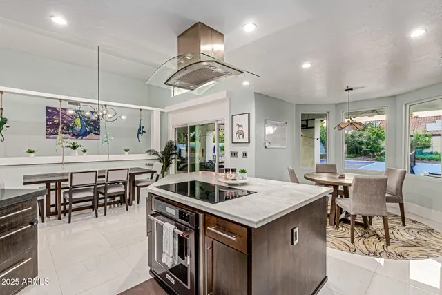 a kitchen with granite countertop a table chairs and white cabinets