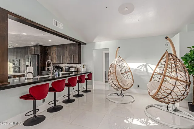 a kitchen with stainless steel appliances a refrigerator a sink a dining table and chairs