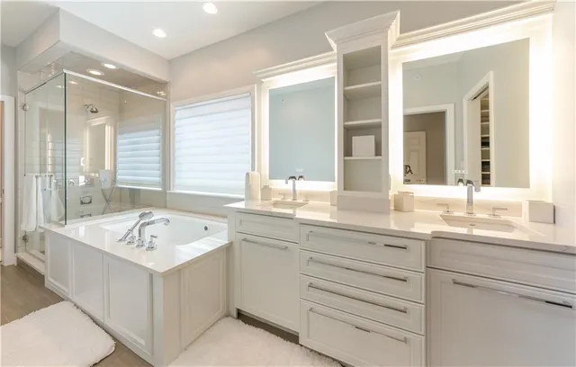 a bathroom with a sink double vanity granite tub shower and a mirror