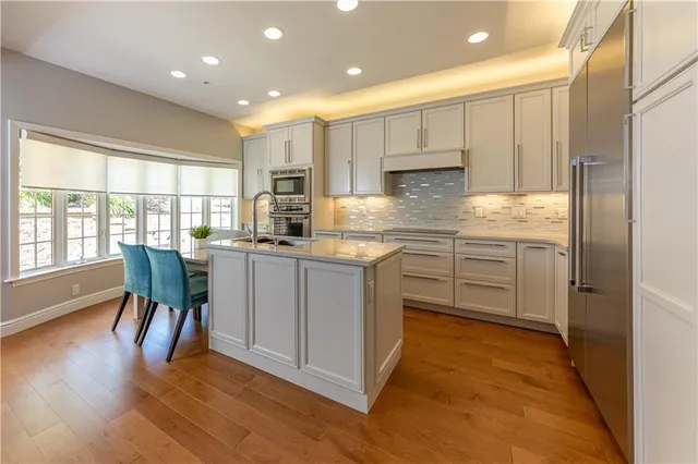 a kitchen with kitchen island granite countertop a sink a stove a refrigerator and island with wooden floor