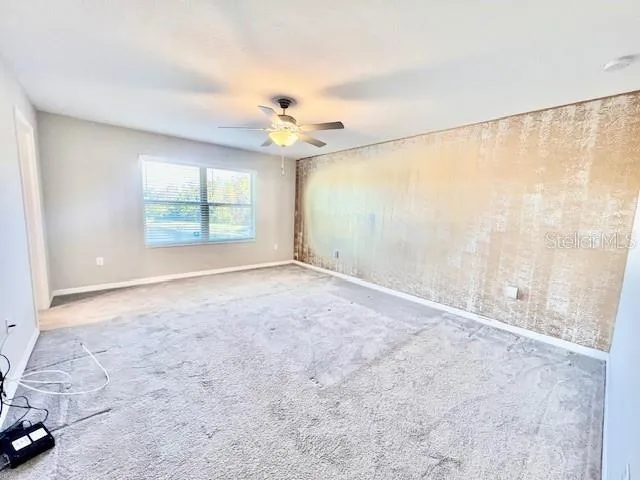 an empty room with fan and windows