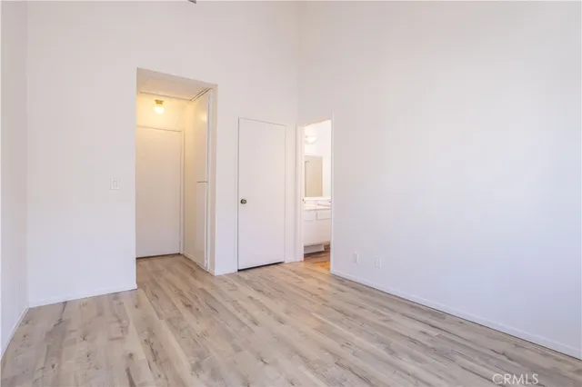 a view of an empty room with wooden floor and a bathroom