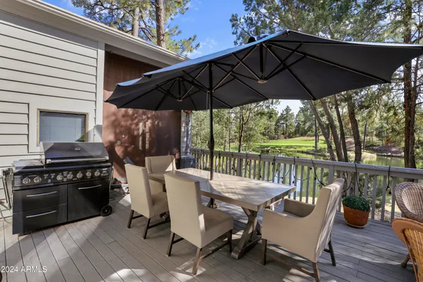 a view of a patio with couches table and chairs under an umbrella