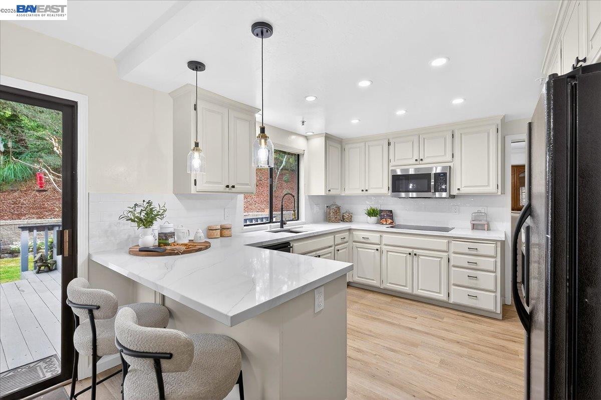 a kitchen with stainless steel appliances kitchen island granite countertop a stove a sink a refrigerator and white cabinets with wooden floor