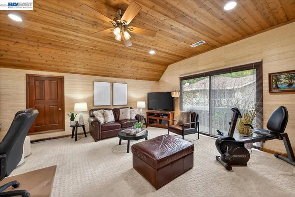 a living room with furniture a ceiling fan a fireplace and a large window