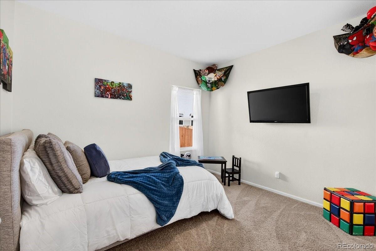7227 Vermillion Street Frederick, CO 80530 - Photo 17 of 28 a bedroom with a bed and a flat screen tv