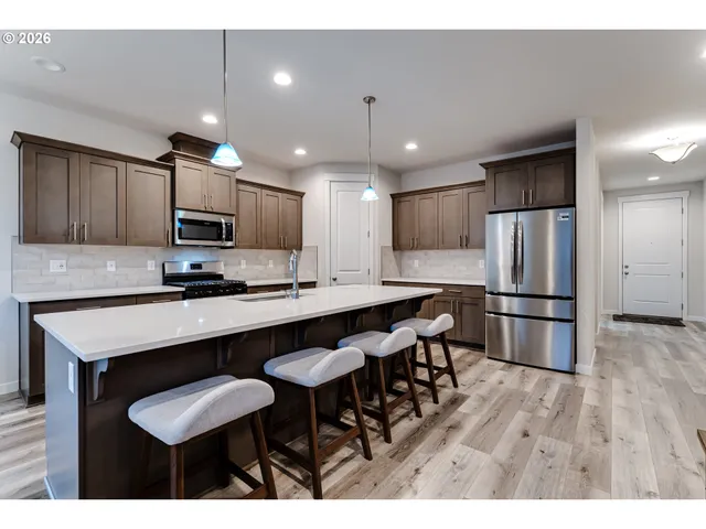 a kitchen with stainless steel appliances wooden floor dining table and chairs