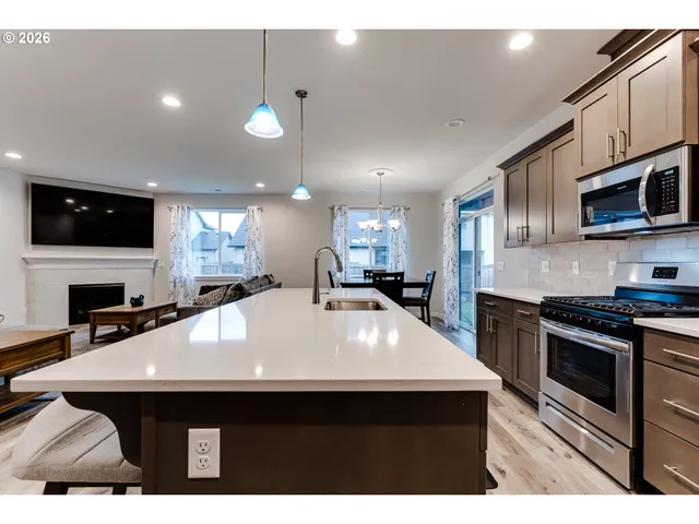 a kitchen with stainless steel appliances a sink a microwave a stove a refrigerator a microwave oven with cabinets