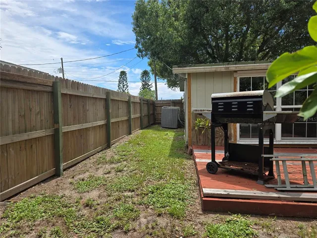 a view of backyard with barbeque grill potted plants and wooden fence