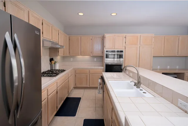 a kitchen with stainless steel appliances a refrigerator sink and white cabinets