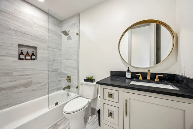 a bathroom with a granite countertop toilet a sink and a mirror