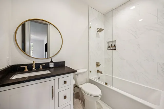 a bathroom with a granite countertop sink toilet and a mirror