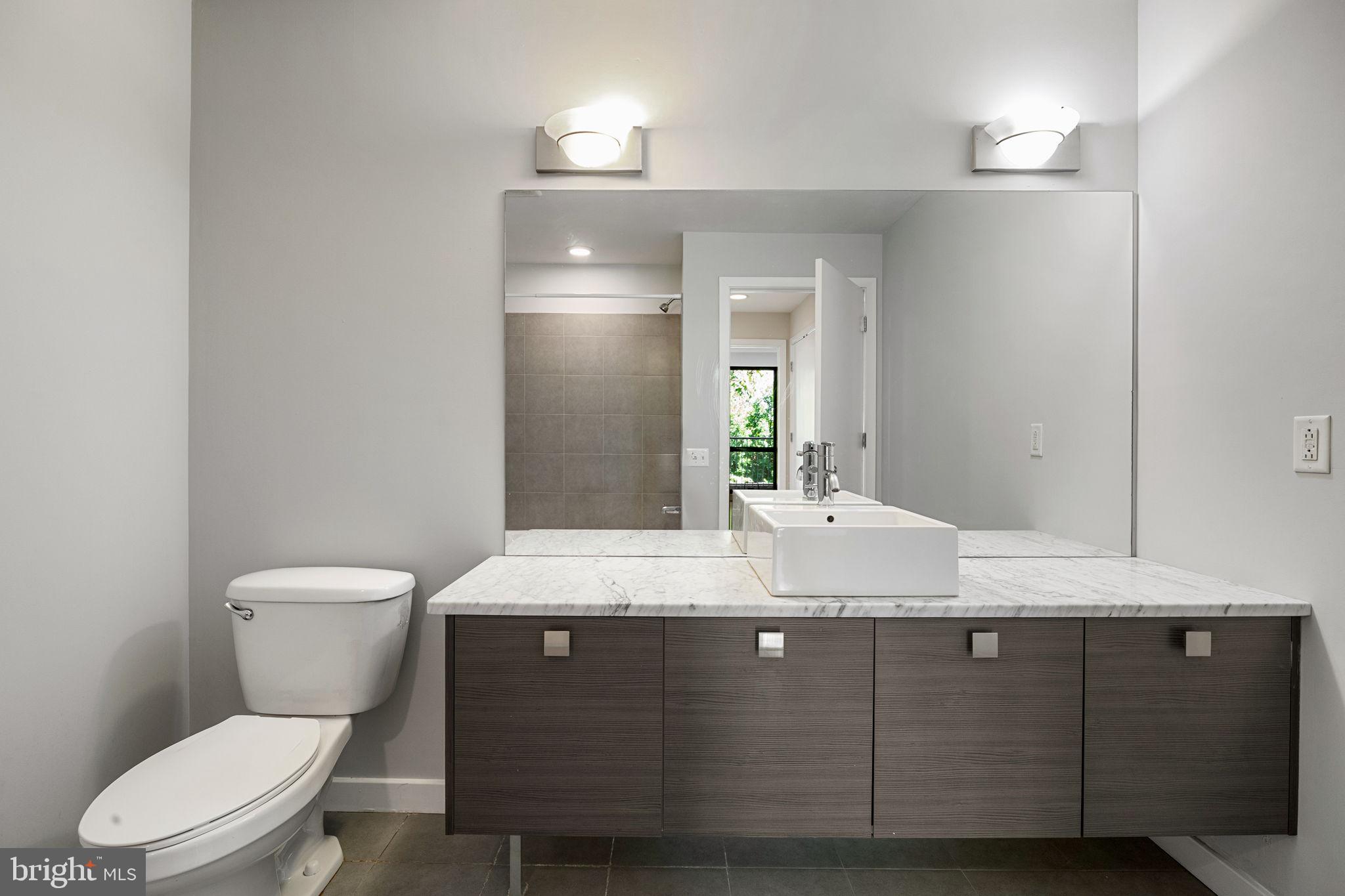 934 North 3rd Street, Unit 205 Philadelphia, PA 19123 - Photo 20 of 39 a bathroom with a granite countertop toilet a sink and a mirror
