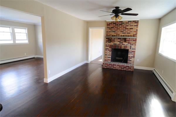 96 Adams Road Grafton, MA 01536 - Photo 8 of 24 an empty room with wooden floor a fireplace and windows