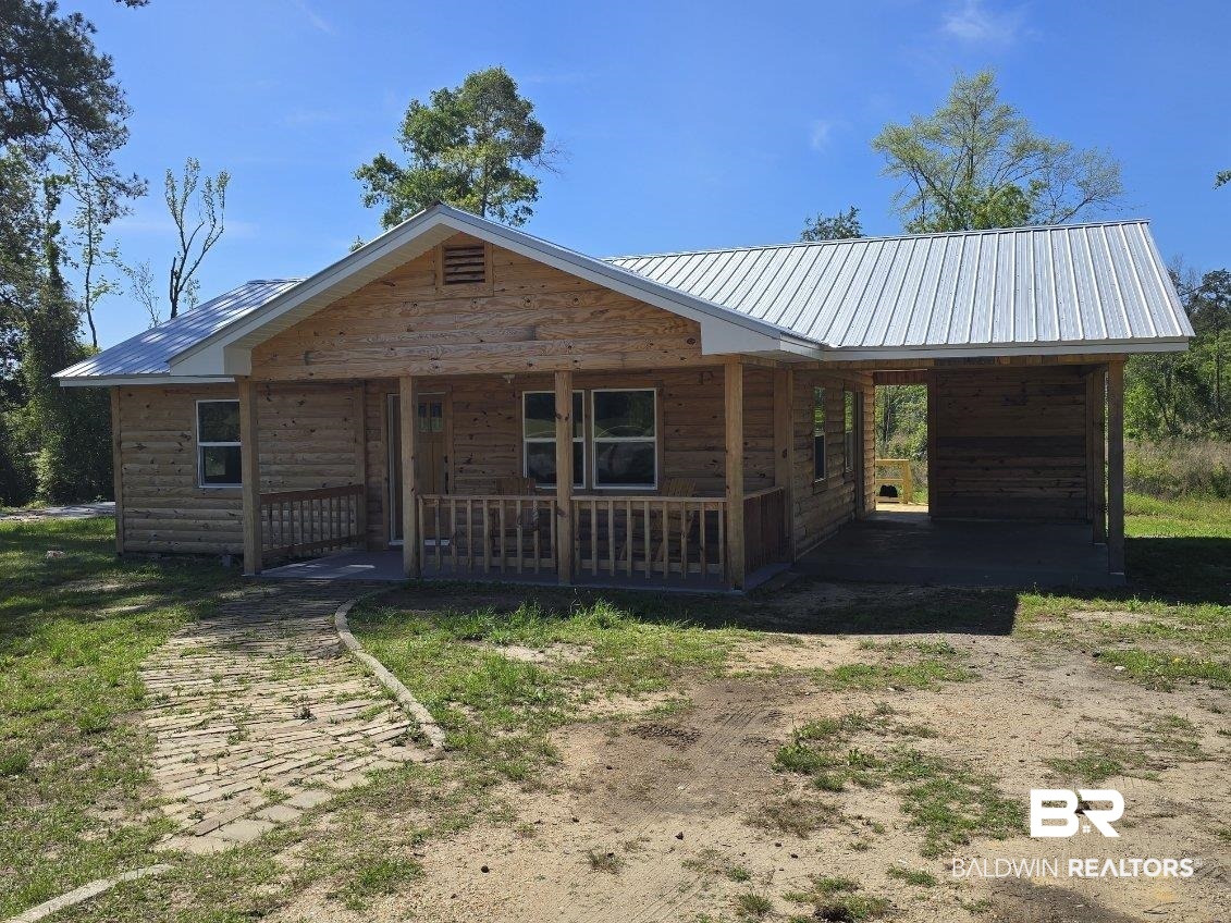 6464 Ridge Road Brewton, AL 36426 - Photo 2 of 14 View of front of property with an attached carport, a metal roof, driveway, and faux log siding