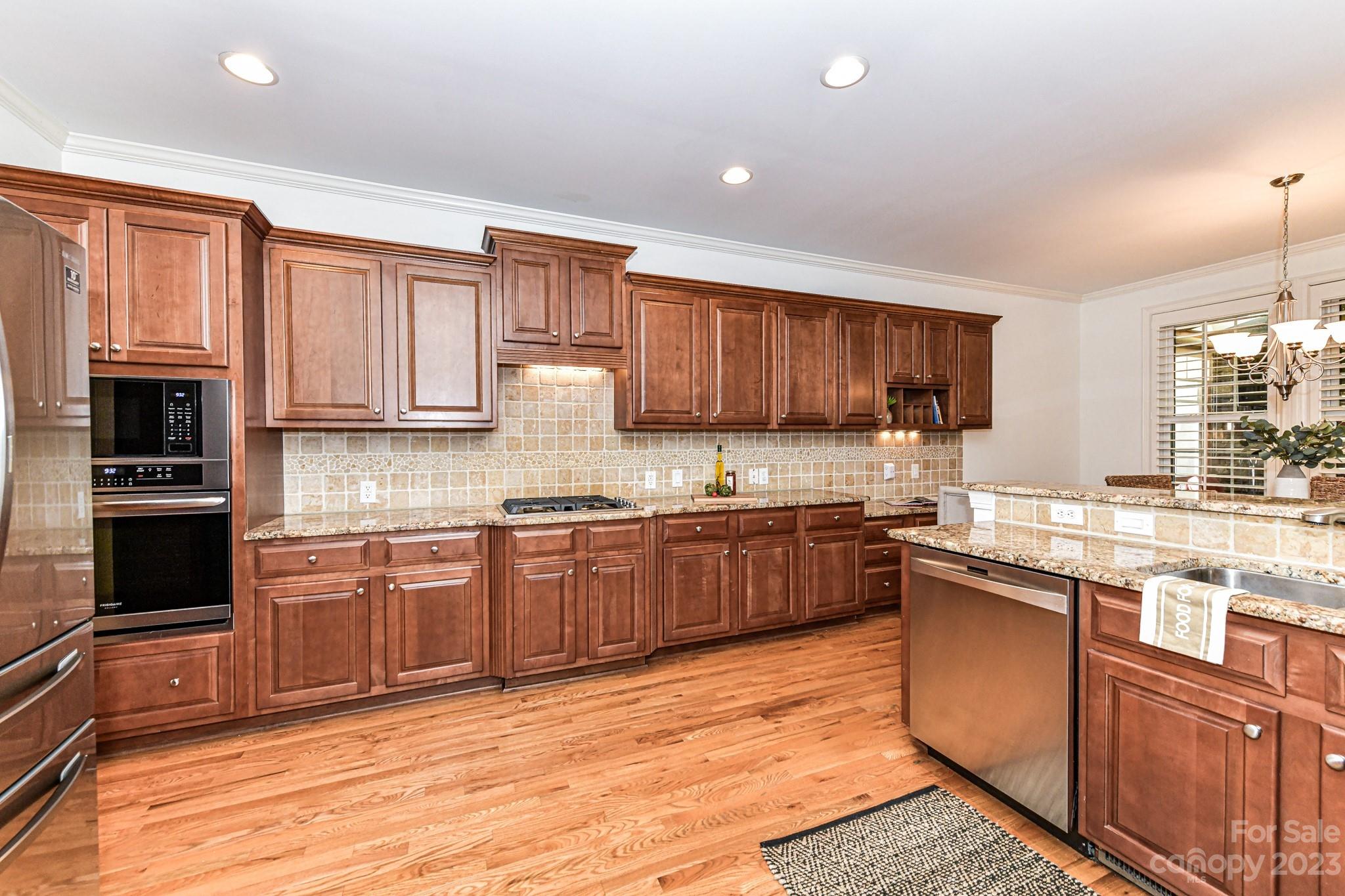 4030 Fawn Hill Road Matthews, NC 28105 - Photo 6 of 48 a kitchen with stainless steel appliances granite countertop a stove top oven a sink dishwasher a dining table and chairs with wooden cabinets