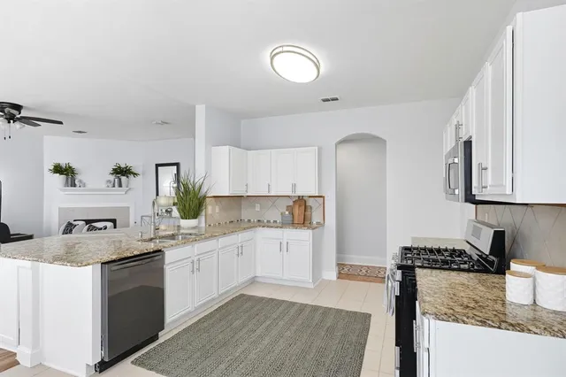 a kitchen with a sink dishwasher and white cabinets with wooden floor