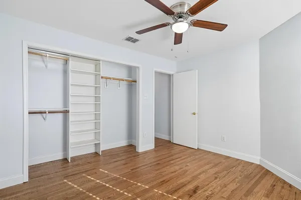 an empty room with closet and ceiling fan