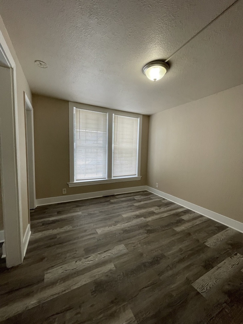 11634 South Princeton Avenue Chicago, IL 60628 - Photo 12 of 18 an empty room with wooden floor and windows