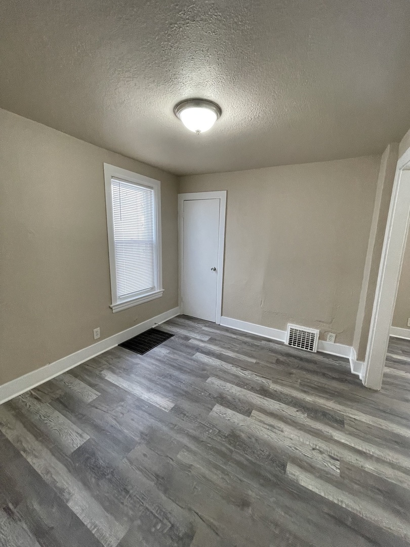 11634 South Princeton Avenue Chicago, IL 60628 - Photo 7 of 18 an empty room with wooden floor and window