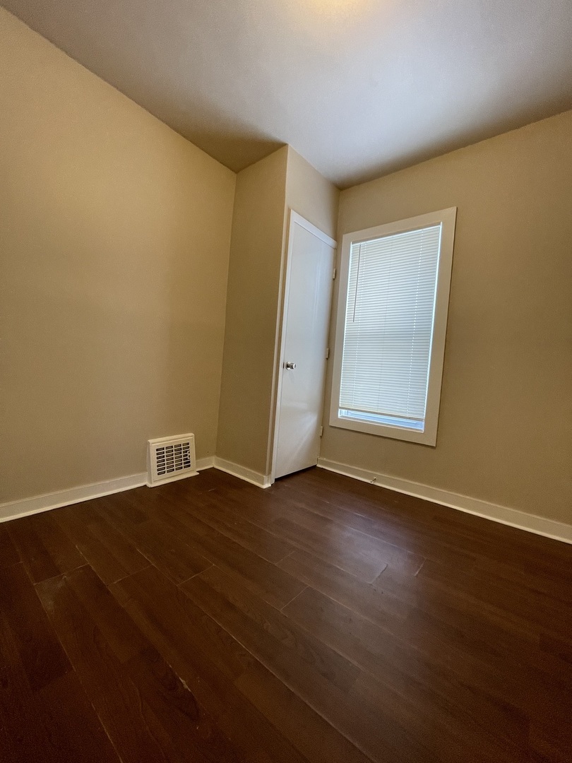 11634 South Princeton Avenue Chicago, IL 60628 - Photo 9 of 18 an empty room with wooden floor and windows