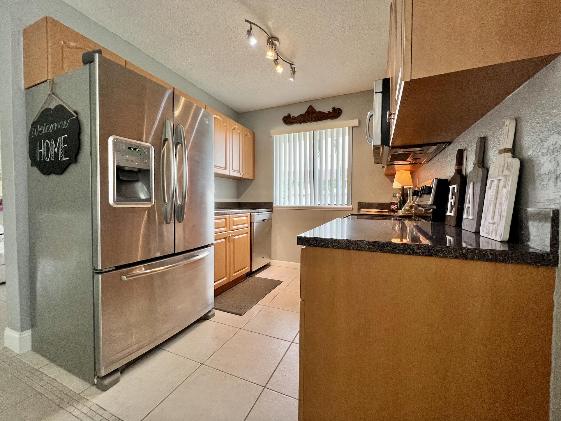 600 Nottingham Circle Greenacres, FL 33463 - Photo 8 of 19 a kitchen with stainless steel appliances granite countertop a refrigerator a stove and a sink with wooden floor