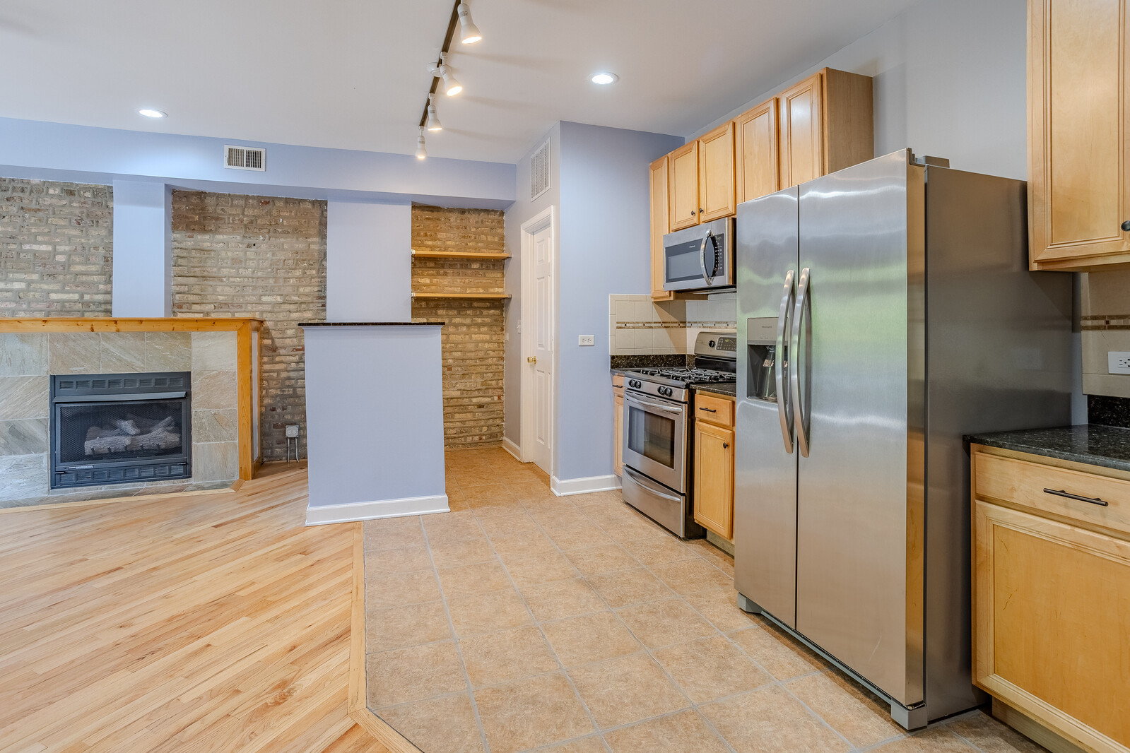 3100 West Addison Street, Unit 1A Chicago, IL 60618 - Photo 7 of 29 a kitchen with stainless steel appliances granite countertop a refrigerator a stove and a sink with wooden floor