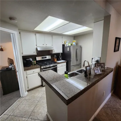 a kitchen with granite countertop a sink dishwasher stove and oven