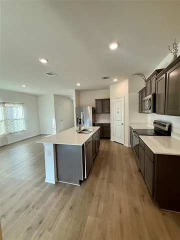 a large kitchen with a center island and wooden floor