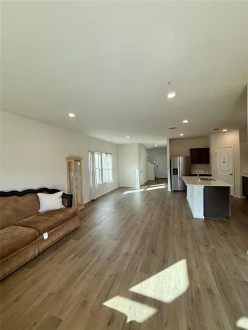 a living room with furniture and kitchen view with wooden floor