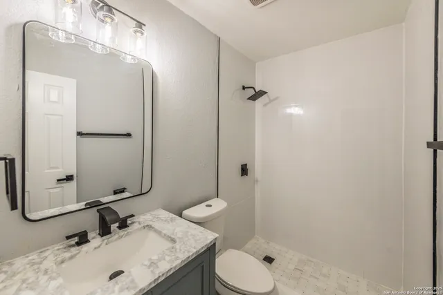 a bathroom with a granite countertop sink toilet and shower