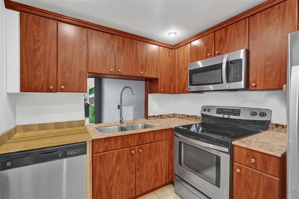 9235 Lagoon Place, Unit 207 Davie, FL 33324 - Photo 13 of 59 a kitchen with granite countertop wood cabinets stainless steel appliances and a sink