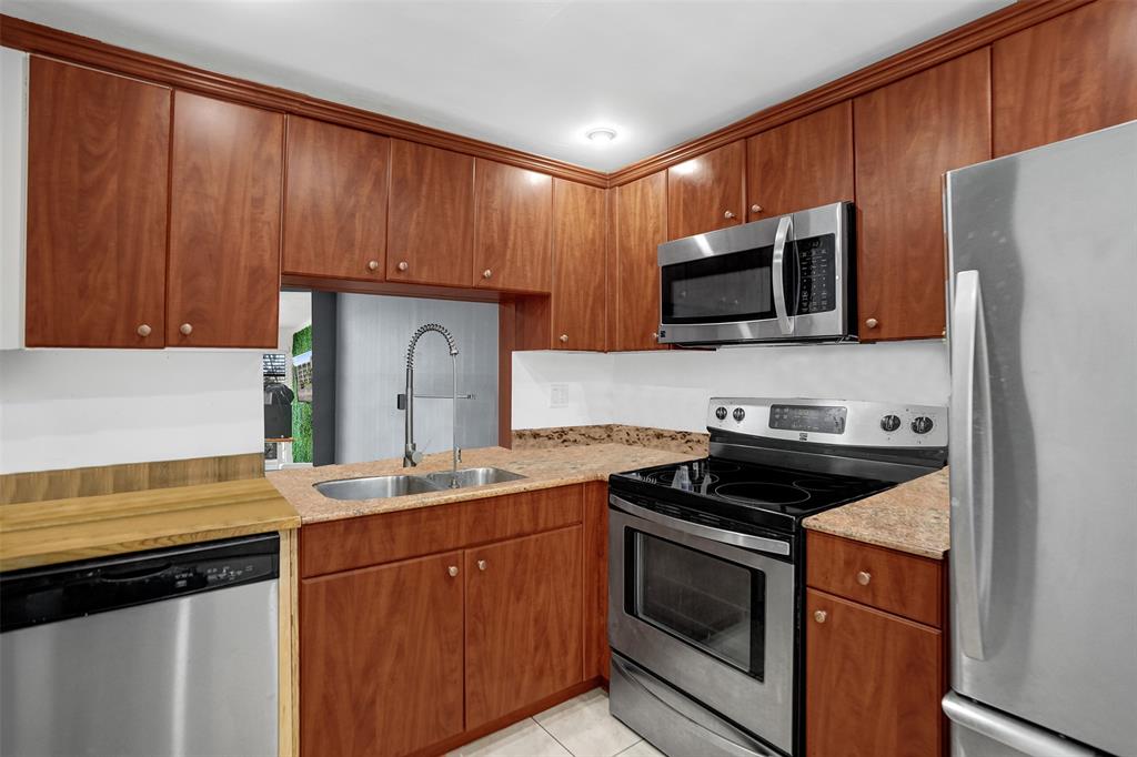 9235 Lagoon Place, Unit 207 Davie, FL 33324 - Photo 16 of 59 a kitchen with granite countertop wooden cabinets and black appliances