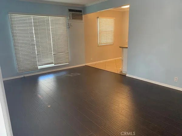 an empty room with wooden floor and windows with curtains