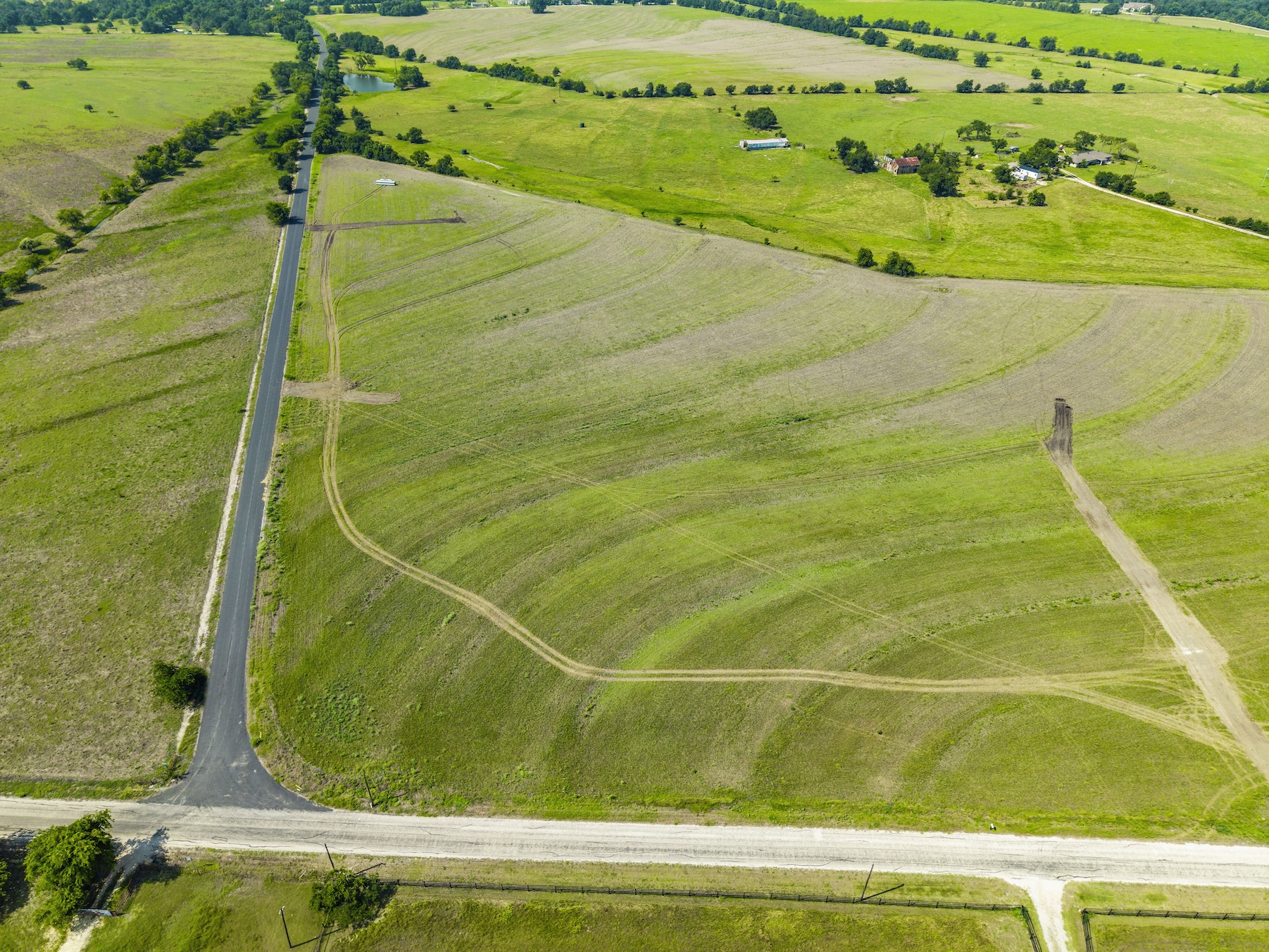 1 County Road 327 Road Granger, TX 76530 - Photo 27 of 27 Gently rolling green pastures stretch toward the horizon along a paved country road.