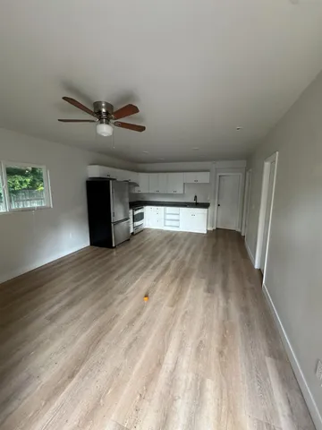 a view of empty room with wooden floor and fan