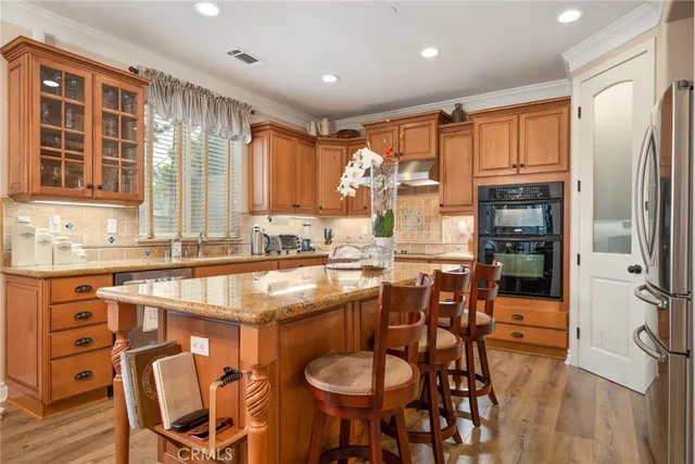 a kitchen with stainless steel appliances granite countertop a table chairs stove and wooden cabinets