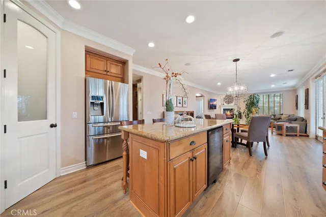 a kitchen with stainless steel appliances granite countertop a refrigerator a sink dishwasher a stove and a dining table with wooden floor