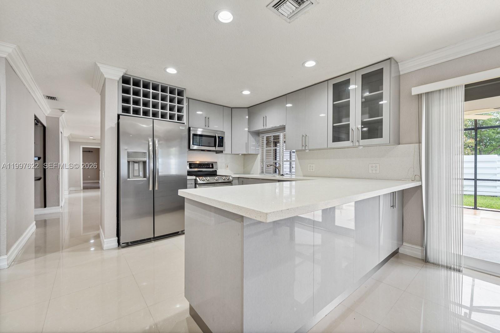 14912 Southwest 143rd Court, Unit 14912 Miami, FL 33186 - Photo 14 of 35 a kitchen with stainless steel appliances kitchen island granite countertop a refrigerator and a sink