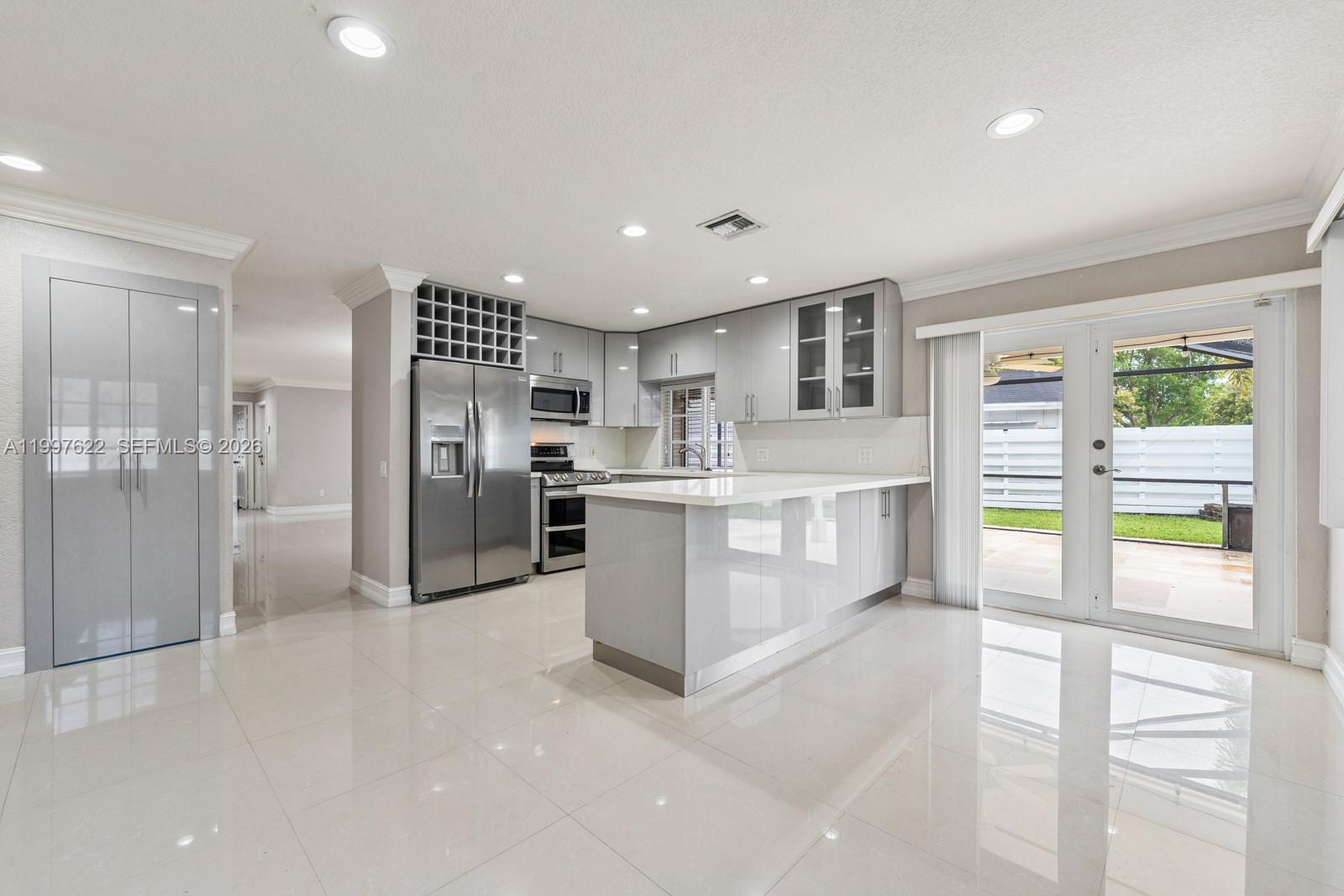 14912 Southwest 143rd Court, Unit 14912 Miami, FL 33186 - Photo 15 of 35 a large white kitchen with stainless steel appliances kitchen island a large counter top and a refrigerator